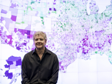 Photo of Sean Reardon in front of U.S. map showing school achievement data