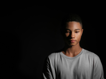 Photo of a Black teenager against a dark background