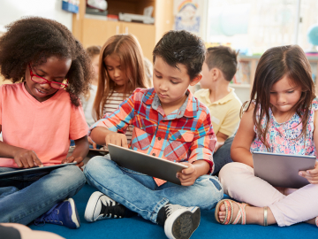 Group of early elementary age students working on tablets