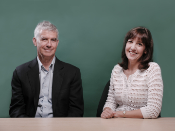 Photo of GSE Dean Dan Schwartz and Senior Lecturer Denise Pope sitting at a table, smiling at the camera