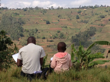 A young student takes a reading assessment in the hills of the Gicumbi district in rural Rwanda (Photo by Elliott Friedlander)