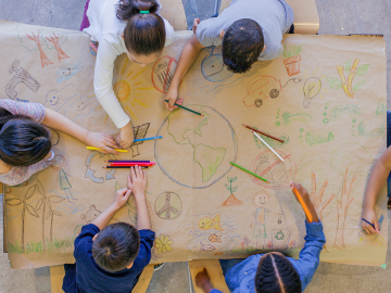 children drawing the earth on a large table