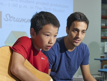Guitar novice Jim Huang, 12, picks a string as he follows the instructions on the interactive web application called Strummify designed by graduate student Danny Cochran, right. (Photo by L.A. Cicero/Stanford News Service)