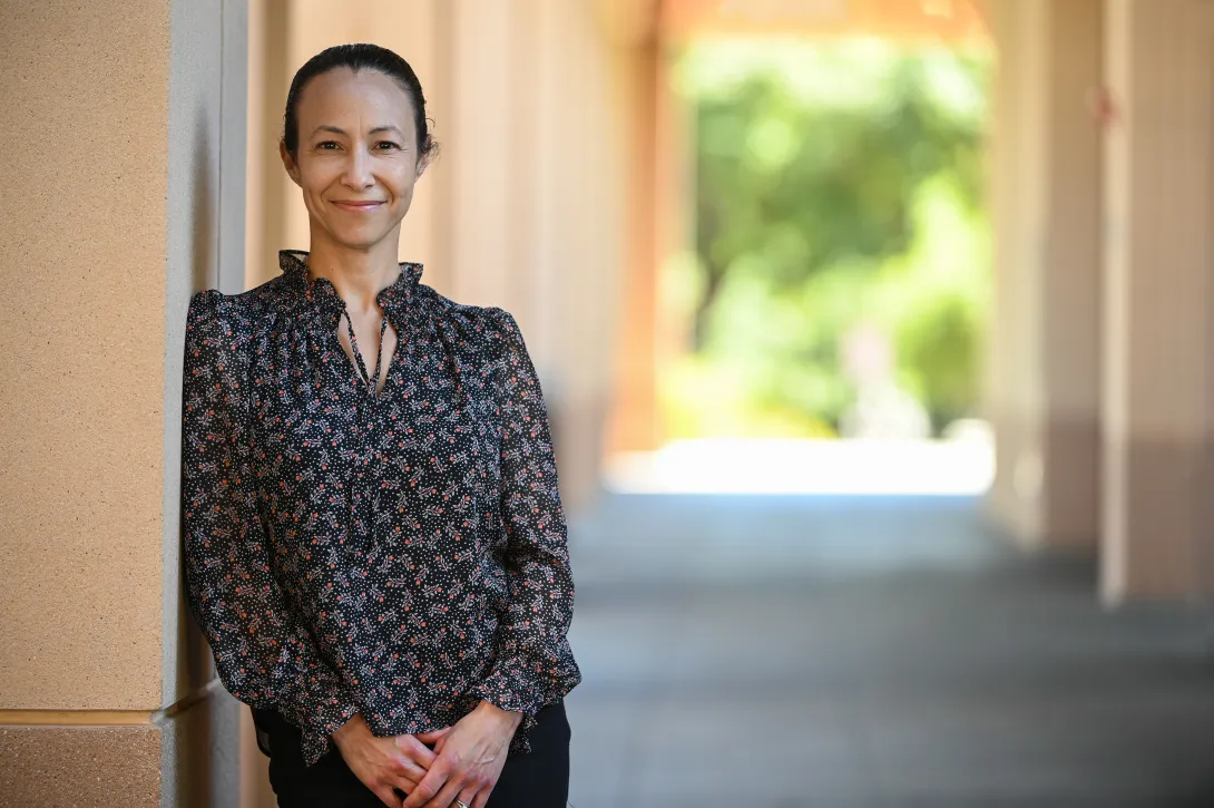 Photo of Emilie Rosales Trimble, smiling, standing in a sunny breezeway