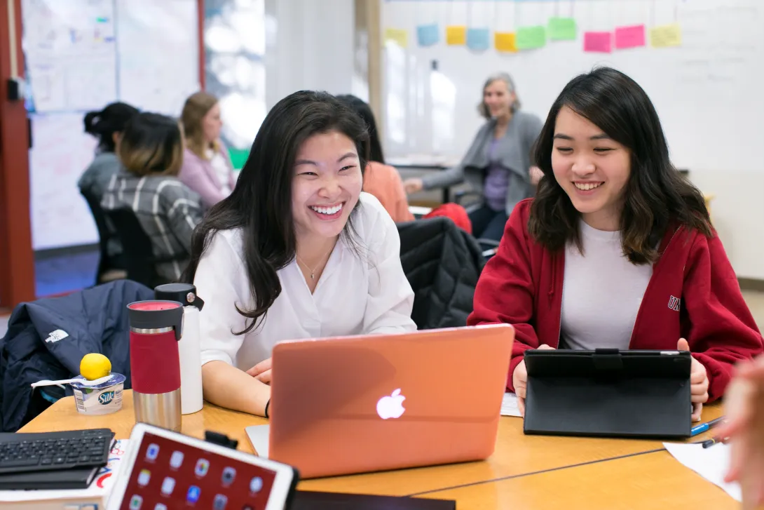 Two female students working on a laptop together.