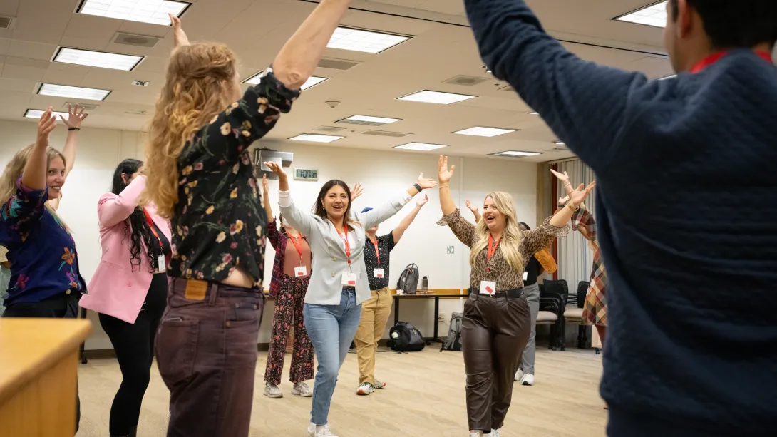 Students participating in at improv session, raising their hands above their heads