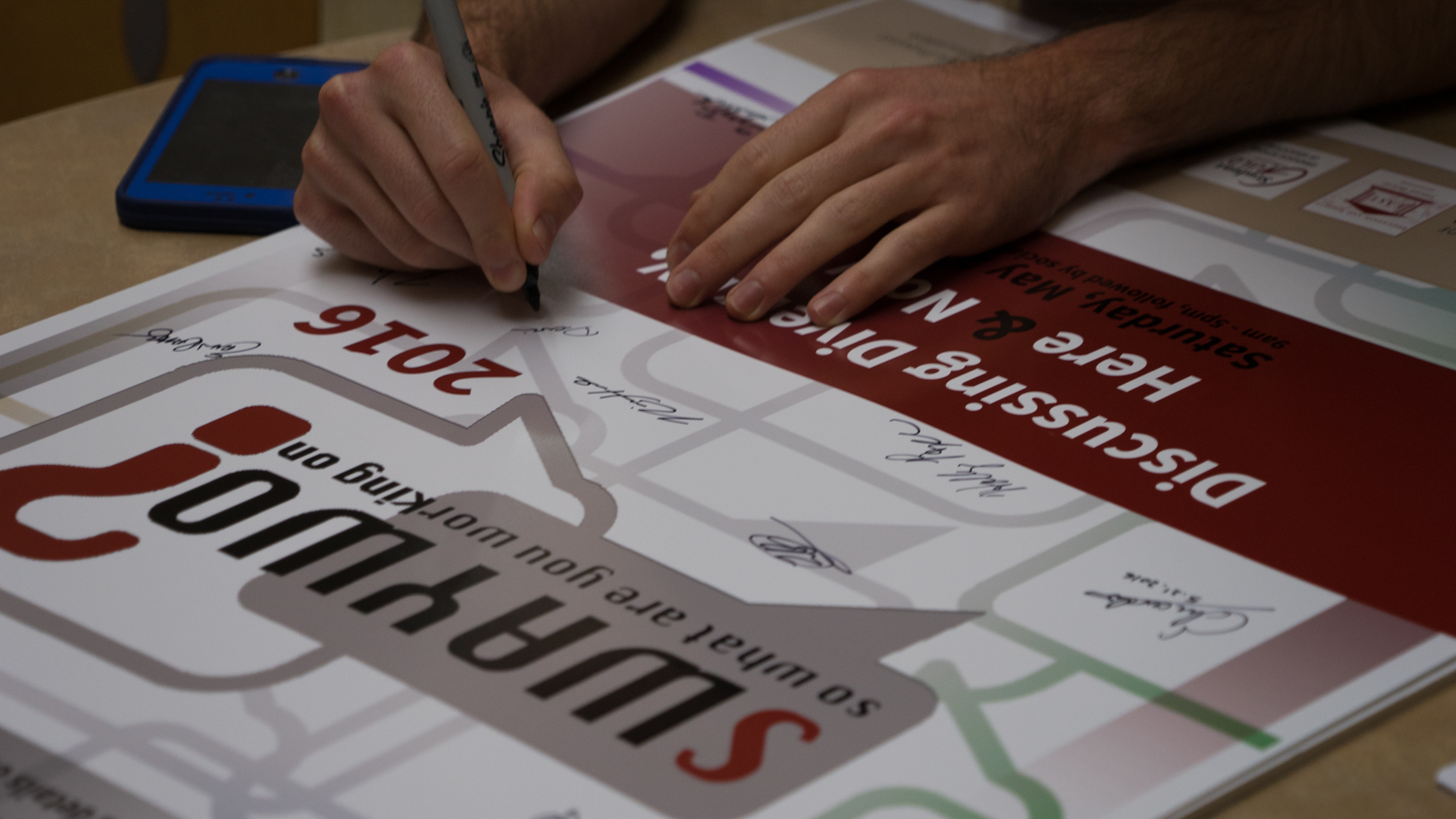 Presenters sign a conference poster to commemorate the second annual SWAYWO conference in 2016. (Photo: March Franklin)